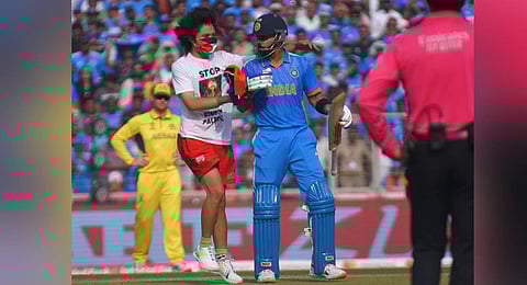 A spectator wearing a t-shirt saying 'Free Palestine' runs on to the pitch as Virat Kohli looks on during the ICC Men's Cricket World Cup final match in Ahmedabad. (Shiba Prasad Sahu)