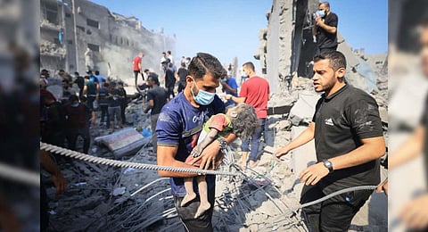 A man carries away a young victim following an Israeli strike on the Bureij refugee camp in the central Gaza Strip on November 2. (Photo | AFP)