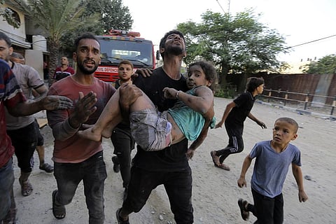 Palestinians carry a wounded girl after being rescued from under the rubble of buildings that were destroyed by Israeli airstrikes in Jabaliya refugee camp. (Photo | AP)