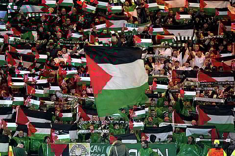 Celtic fans in the stands wave Palestinian flags ahead of the Champions League Group E match between Celtic Glasgow and Atletico Madrid, at Celtic Park in Scotland on October 25, 2023. (Photo | AP)