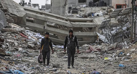 Palestinians walk through destruction in Shati refugee camp. (Photo | AP)