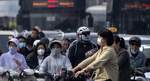 Commuters wearing face masks as they wait at an intersection in the central business district during the morning rush hour in Beijing. (Photo | AP)