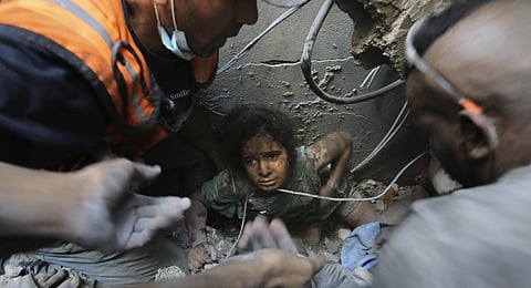 Palestinians try to pull a girl out of the rubble of a building that was destroyed by Israeli airstrikes in Jabaliya refugee camp, northern Gaza Strip. (Photo | AP)