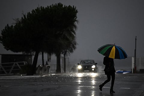 A woman holding an umbrella crosses a street under the rain ahead of storm Ciaran on November 1. (Photo | AFP)