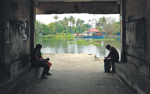 Two people wait at Vaduthala jetty for a boat to Korangotta