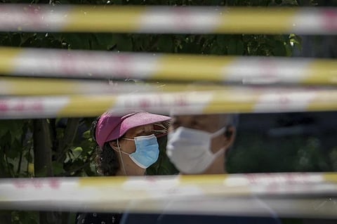 FILE - Residents wearing face masks line up behind barricaded tapes for COVID mass testing near a residential area on May 15, 2022, in Beijing. (Photo | AP)