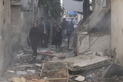 Palestinians walk by a damaged building following an Israeli army operation in Jenin refugee camp, West Bank, Sunday, Nov. 26, 2023. (Photo | AP)