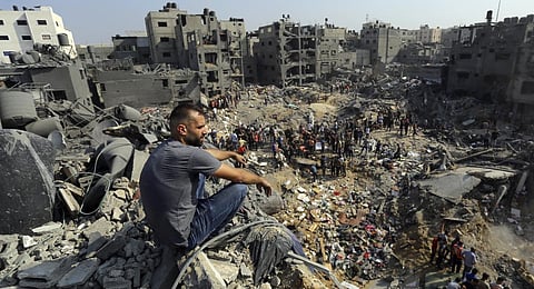 A man sits on the rubble overlooking the debris of buildings that were targeted by Israeli airstrikes in the Jabaliya refugee camp.(Photo | AFP)