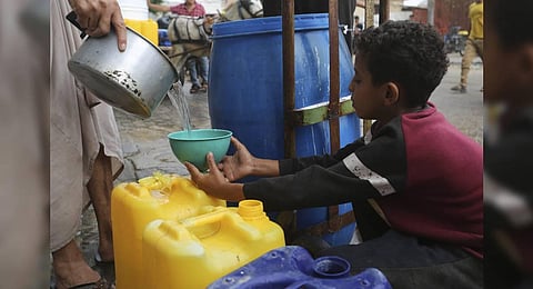 A Palestinian fills a cup with drinking water during the ongoing Israeli bombardment of the Gaza Strip | AP
