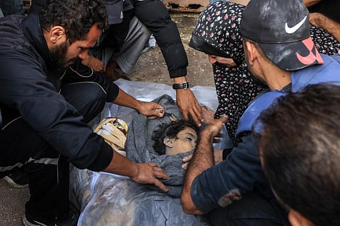 Palestinian cameraman Mohammed Alaloul (R) uncovers the body of one of his children killed in an Israeli strike on the Al-Maghazi refugee camp in Deir Balah in the central Gaza Strip. (Photo | AFP)