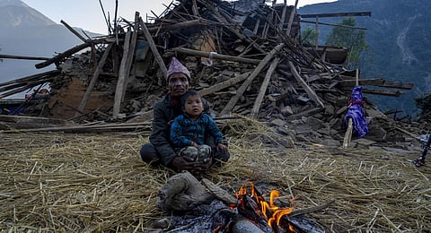 A man and a child sit in front of earthquake damaged house in Jajarkot district, northwestern Nepal. (Photo | AP)