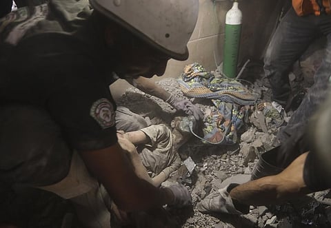 Palestinians rescue a wounded girl from under the rubble of a destroyed building following an Israeli airstrike in Khan Younis. (Photo | AP)
