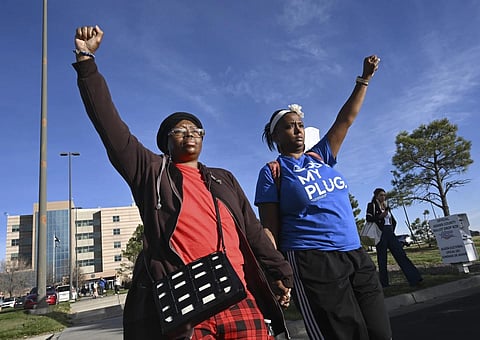 Sheneen McClain, left, mother of Elijah McClain, and friend and supporter MiDian Holmes clasp hands as they hold up their fists in protest, Nov 6, 2023. (Photo | AP)
