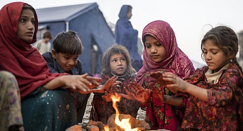 Afghan refugee children warm themselves with fire in a camp near the Torkham Pakistan-Afghanistan border in Torkham, Afghanistan.(Photo | AP)