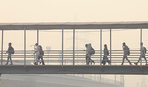 Commuters crossing a foot-over bridge amid smog in Gurugram on Wednesday | PTI