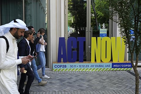 A group walks near a sign that reads 'act now' at the COP28 UN Climate Summit, Sunday, Dec. 10, 2023, in Dubai, United Arab Emirates. (AP Photo)