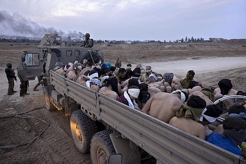 Israeli soldiers stand by a truck packed with bound and blindfolded Palestinian detainees, in Gaza. (Photo | AP)