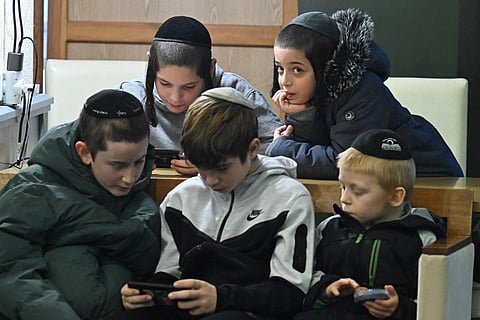 Jewish boys play with their mobile phone at the Balatonszöd refugee camp operated by the Association of Hungarian Jewish Communities (EMIH) on November 28, 2023. (Phone | AFP)