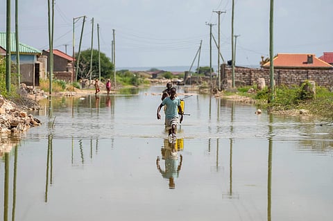 People wade through a section of a road destroyed by floods in Mandera County, Kenya on Wednesday, December 13, 2023. (Photo | AP)
