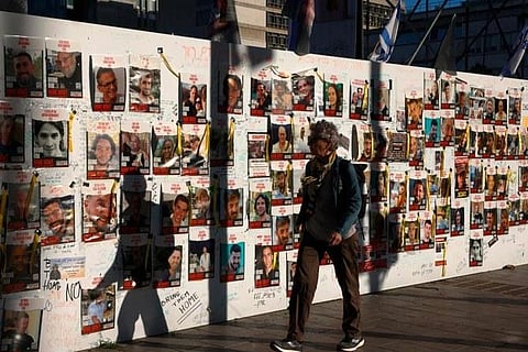 People pass by portraits of Israeli hostages held in Gaza since the October 7 attacks by Palestinian Hamas militants, posted on a wall in Tel Aviv amid the war. (Photo | AFP)