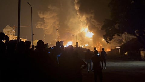 Residents watch a plume of smoke from a burning oil depot, in Conakry, Guinea, Monday. (Photo | AP)