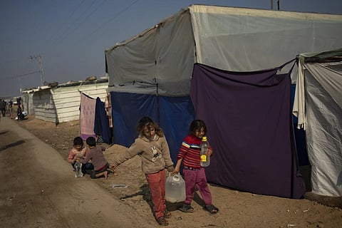 Palestinian children displaced by the Israeli bombardment of the Gaza Strip carry water in the makeshift tent camp, Dec 18, 2023. (Photo | AP)