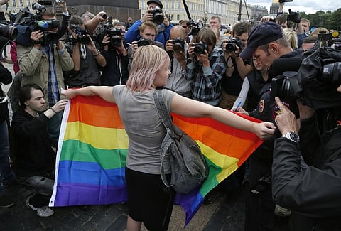 A gay rights activist stands with a rainbow flag, in front of journalists, during a protesting picket at Dvortsovaya (Palace) Square in St.Petersburg, Russia, Sunday, Aug. 2, 2015. (Photo | AP)