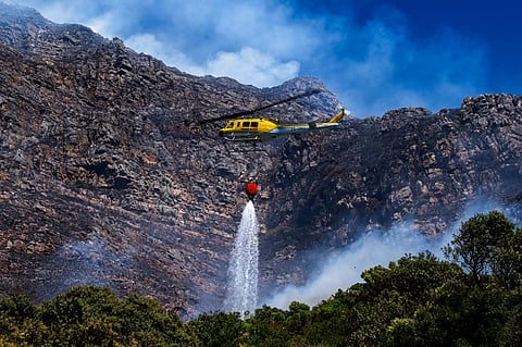 A fire fighting helicopter battles a vegetation fire on the slopes above Simon's Town, around 40 kilometers (25 miles) south of Cape Town, South Africa, Tuesday, December 19, 2023. (Photo | AP)