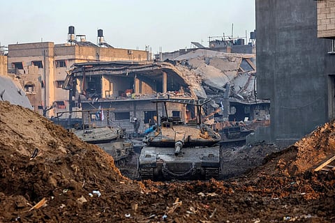 Israeli tank rolling past damaged buildings during a military operation in the north of the Gaza Strip amid continuing battles between Israel and the Palestinian militant group Hamas.