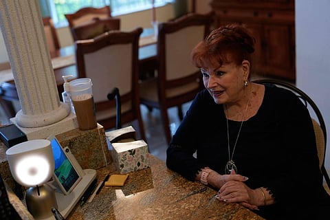 Deanna Dezern, 83, prompts her ElliQ, left, a tabletop device that uses artificial intelligence to conduct human-like conversations. (Photo | AP)