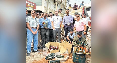 A team of excise department officials with the accused and the seized liquor, in Belagavi on Friday | Express