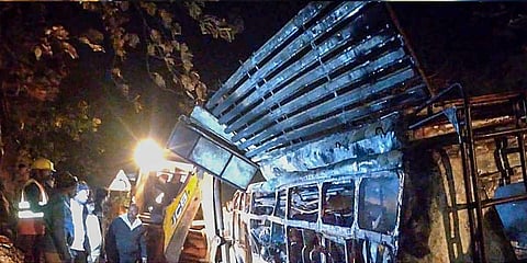 Rescue officials stand near the charred remains of a bus that caught fire after colliding with a dumper in Guna district, Wednesday, Dec. 27, 2023. (Photo | PTI)