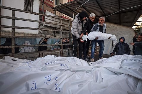The shrouded bodies of people killed in Rafah during Israeli bombardment on the southern Gaza strip, are placed on a truck for burrial outside Al-Najar hospital on December 29, 2023. | AFP
