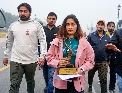 Wrestler Vinesh Phogat walks with her Arjuna and Khel Ratna Awards, India's highest national sports awards, before leaving them on a pavement near the prime minister's office| PTI