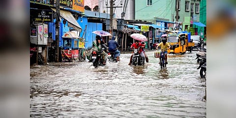 Commuters on a road waterlogged due to heavy rain owing to Cyclone Michaung, in Tirupati, Andhra Pradesh. (Photo | PTI)