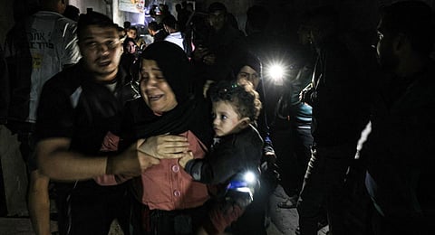 A woman carrying a child is helped by a man following an Israeli strike in Rafah in the southern Gaza Strip on December 6, 2023. (Photo | AFP)