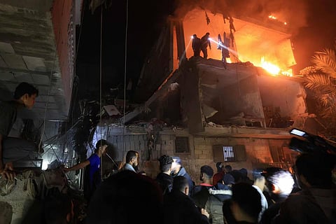 People use the lights on their telephones to search for victims amid the rubble of a smouldering building, following an Israeli strike in Rafah on December 6, 2023. (Photo | AFP)