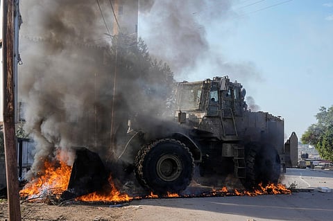 An Israeli army vehicle removes tires blocking roads that Palestinians had set on fire during a military raid into Faraa refugee camp, West Bank on Friday, December 8, 2023.