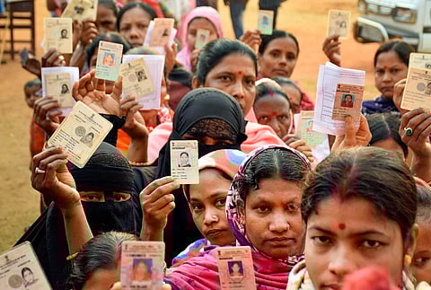 Voters show their identification cards as they wait in queues to cast their votes at a polling booth during the Tripura Assembly elections. (Photo | PTI)