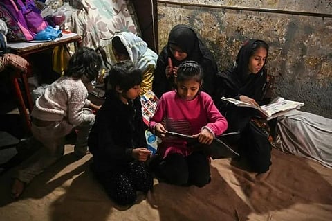Daughters of Muhammad Amin, a security guard, study at their home in Lahore. (Photo | AFP)