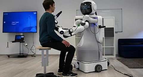 An employee sits in front of the robot Garmi in the laboratory of the Research Center Geriatronics of the Technical University Munich, in Garmisch-Partenkirchen, southern Germany. (Photo | AFP)