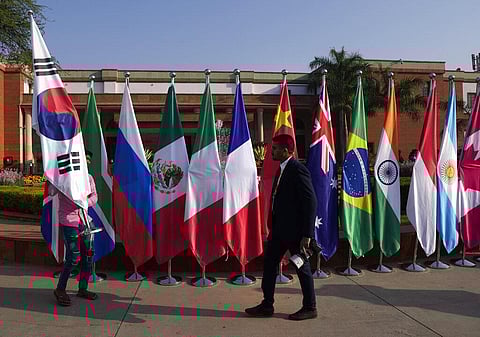 A worker carries flags of participating countries to be placed at the opening session of the G20 foreign ministers meeting, in New Delhi, India on Thursday, March 2, 2023. (Photo |AP0