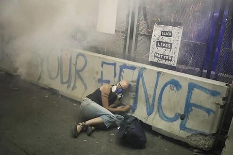 FILE - A demonstrator hides under a barrier as federal officers release tear gas during a Black Lives Matter protest at the Mark O. Hatfield United States Courthouse, July 29, 2020. (Photo | AP)