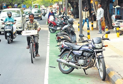 With two-wheelers parked on the cycling track near Ernakulam General Hospital, a lottery seller on a bicycle is forced to use the main road