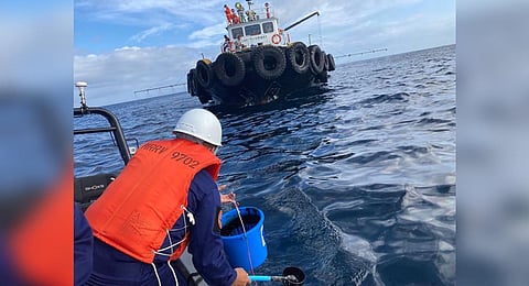 In this handout photo received from the Philippine Coast Guard and taken on March 2, 2023, a coast guard personnel collects water sample from of an oil spill in the waters off Naujan. (Photo | AFP)