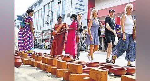 Foreign tourists walk past pots and bricks kept for sale for the Attukal Pongala festival in Thiruvananthapuram | Vincent Pulickal
