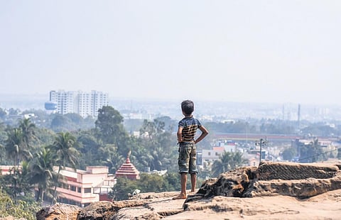 A boy atop the Khandagiri hill looks at the Bhubaneswar cityscape. (Photo | Debadatta Mallick)