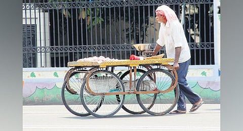 A vendor seen covering his head to protect himself from the heat | G Satyanarayana