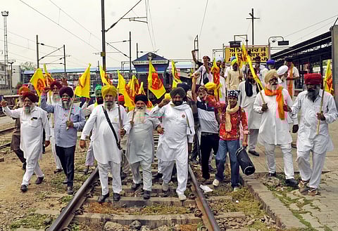 Farmers block railway tracks during a protest against the government’s alleged decision to impose a price cut on the damaged wheat crop, in Amritsar on Tuesday. (Photo | ANI)