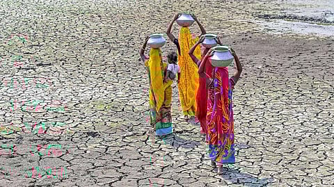 Women carry pots filled with drinking water on their heads through a dry pond in a drought-like situation due to the heatwave.(Representative Image)
